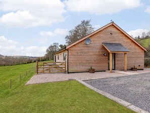 A wooden barn-style building with a gravel driveway and a wooden gate. - 5 Bed in Dulverton (oc-87003) (Morebath)