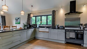 A modern kitchen with a large island, stainless steel appliances, and pendant lighting. - 5 Bed in Dulverton (oc-87003) (Morebath)