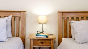 Ein Schlafzimmer mit zwei Betten, einem Nachttisch mit Lampe und einer Schublade.