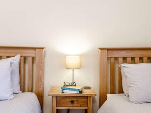 Ein Schlafzimmer mit zwei Betten, einem Nachttisch mit Lampe und einer Schublade.