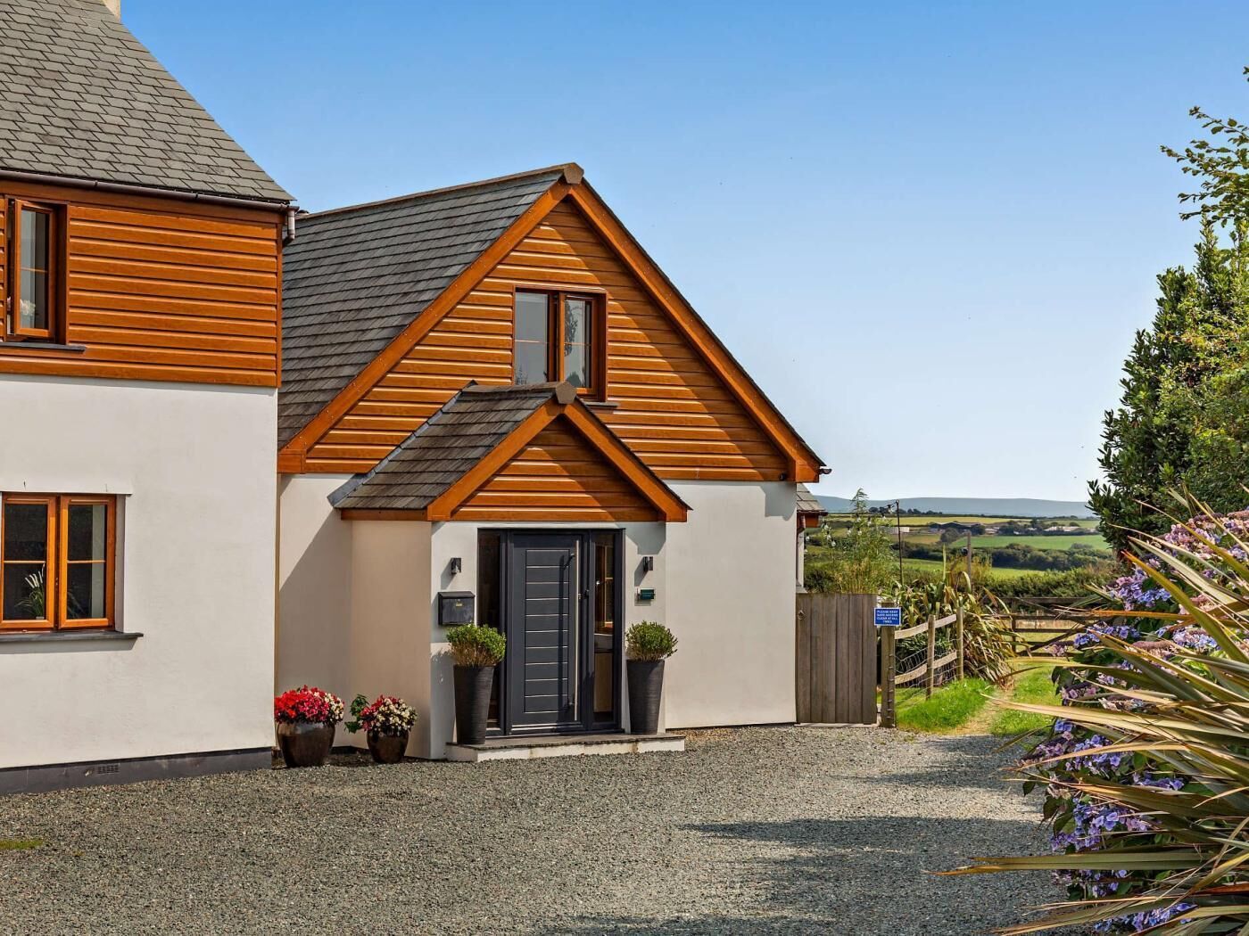 A two-story house with a sloped roof, a front door, and a gravel driveway.