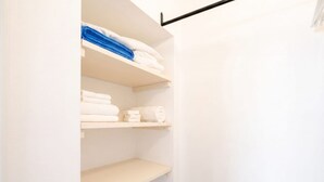 A closet with shelves holding folded towels and a black rod above. - English	Italian Elegant Balcony Retreat in Polignano Centro (Polignano a Mare)