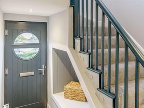 A dark wooden door with a window, a white wall, and a staircase with beige carpet and black railings. - 3 Bed in New Quay (oc-83998) (New Quay)