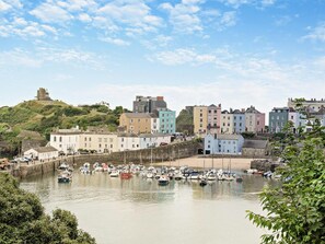 A coastal town with colorful buildings, a historic tower, and a marina with boats. - 1 Bed in Tenby (oc-95995) (Tenby)