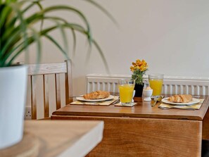A breakfast table with croissants, two glasses of orange juice, and a small potted plant.