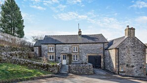 Une maison en pierre avec une porte d’entrée, un garage et une cheminée.