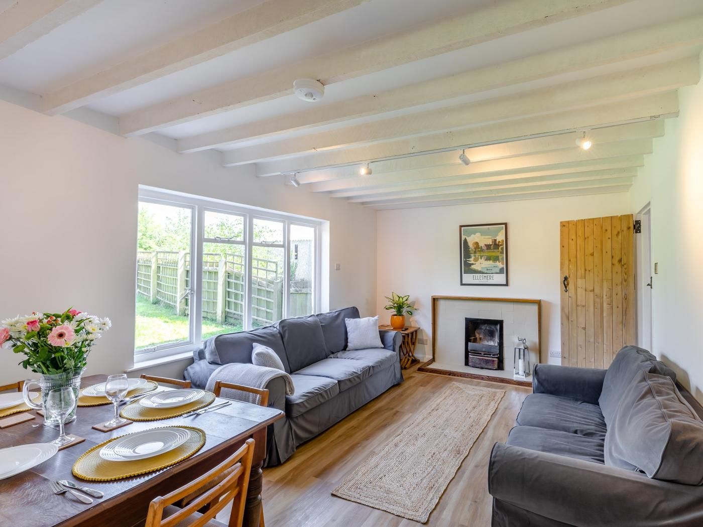 A cozy living room with a sofa, a dining table set for four, and a fireplace.