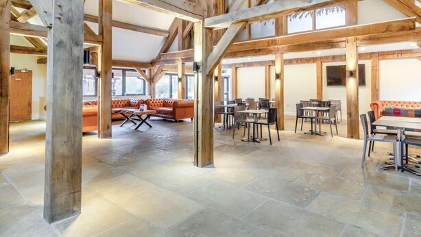 A spacious hall with high wooden beams, stone flooring, and seating areas. - 3 Bed in King's Lynn (oc-96035) (Middleton)