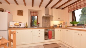 A kitchen with wooden beams, a window with a plaid valance, a built-in oven, and a sink. - 2 Bed in Matlock (oc-75893) (Slaley)