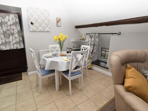 A dining area with a table set for four, chairs, a vase with yellow flowers, and a window with a view. - 2 Bed in Brecon (oc-bn178) (Llanfihangel Nant Bran)