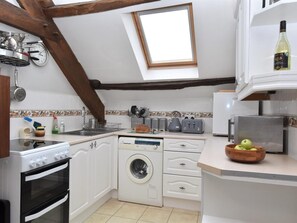 A compact kitchen with a washing machine, a stove, and a small window. - 2 Bed in Brecon (oc-bn178) (Llanfihangel Nant Bran)