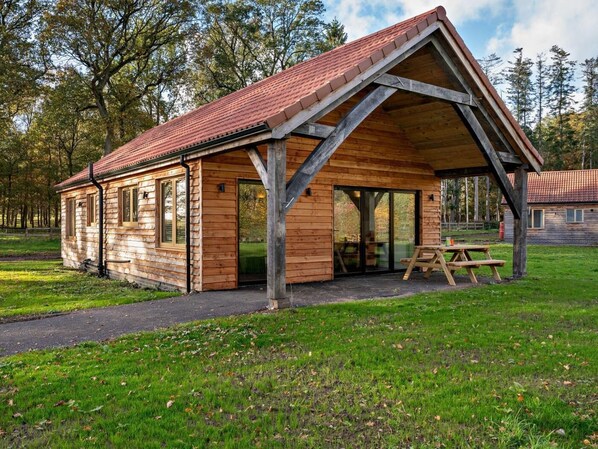 Eine Holzhütte mit Satteldach, großen Fenstern und einer überdachten Terrasse.