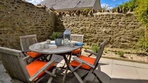 A stone wall, a round wooden table with chairs, and a lantern. - 2 Bed in Beaminster (oc-78567) (Beaminster)