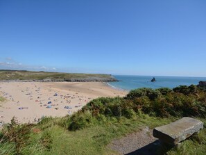 A beach with tents and people, a rocky coastline, and a clear sky.