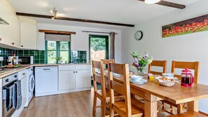 Een moderne keuken met houten kastjes, een eettafel gedekt voor vier personen en een klok aan de muur.