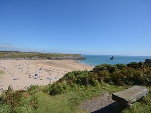 Ein Strand mit Zelten und Menschen, ein Felsvorsprung und ein klarer Himmel.