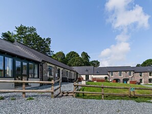A building with a stone facade and large windows, a gravel driveway, and a wooden fence.