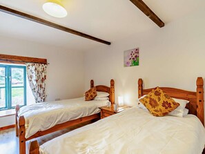 A room with two wooden beds, a window with curtains, a wall-mounted light, and a small picture. - 4 Bed in Pembroke (oc-44351) (Hundleton)