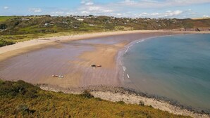 Una spiaggia costiera con una battigia sabbiosa, alcuni veicoli e un cielo sereno.
