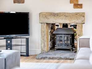 A modern living room with a stone fireplace, a flat-screen TV, and a sofa. - 5 Bed in Halifax (oc-96061) (Sowerby Bridge)
