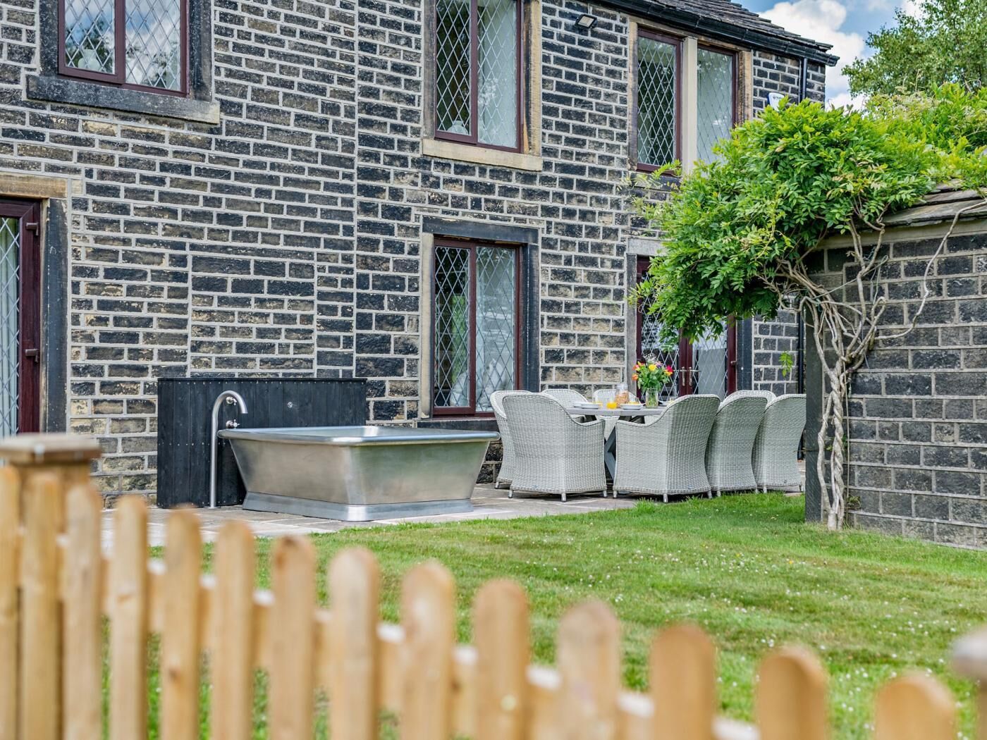 Ein Steinhaus mit Terrasse, Sitzgelegenheiten im Freien und einem eingebauten Whirlpool.