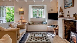 Ein gemütliches Wohnzimmer mit Kamin, Fernseher und einer komfortablen Sitzecke.