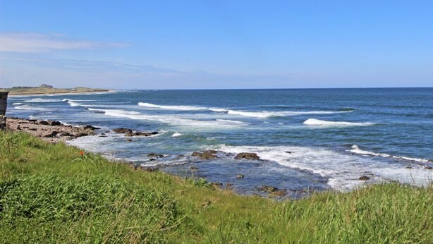 A coastal landscape with a clear sky, waves, and a grassy foreground. - 3 Bed in Seahouses (oc-81486) (Seahouses)