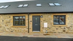A stone building with a dark roof, multiple windows, and a door. - 3 Bed in Seahouses (oc-81486) (Seahouses)