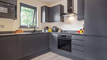 A modern kitchen with dark cabinetry, a built-in oven, and a window providing natural light.