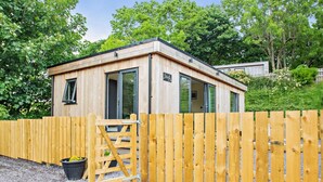 Eine Holzhütte mit Tür, Fenster und einem kleinen Schild.