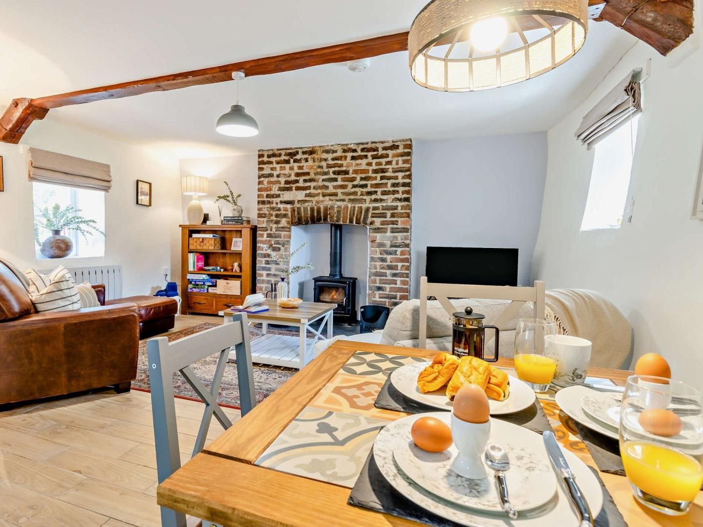 A cozy living room with a fireplace, a dining table set for breakfast, and a comfortable seating area.