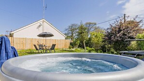 Ein Whirlpool in einem Hinterhof mit Holzlattenzaun, einem Tisch mit Stühlen und einem Haus im Hintergrund.