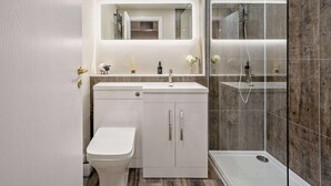 A modern bathroom with a white vanity, a toilet, a glass shower enclosure, and a mirror above the vanity. - 1 Bed in Oban (oc-96079) (Oban)