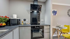 A compact kitchen with a microwave, oven, and a small dining area with a table and chairs. - 1 Bed in Oban (oc-96079) (Oban)