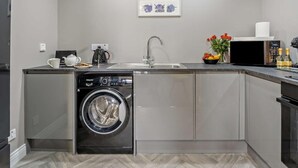 A modern kitchen with a built-in washer, a sink, a microwave, and a coffee maker. - 1 Bed in Oban (oc-96079) (Oban)
