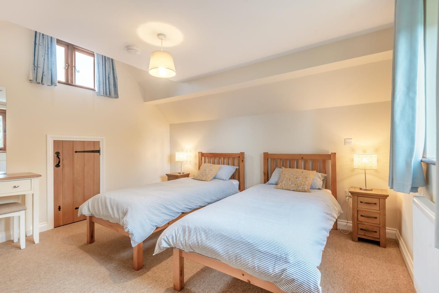 A bedroom with two single beds, a desk, and a wardrobe.