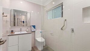 Uma casa de banho moderna com lavatório, sanita e chuveiro.