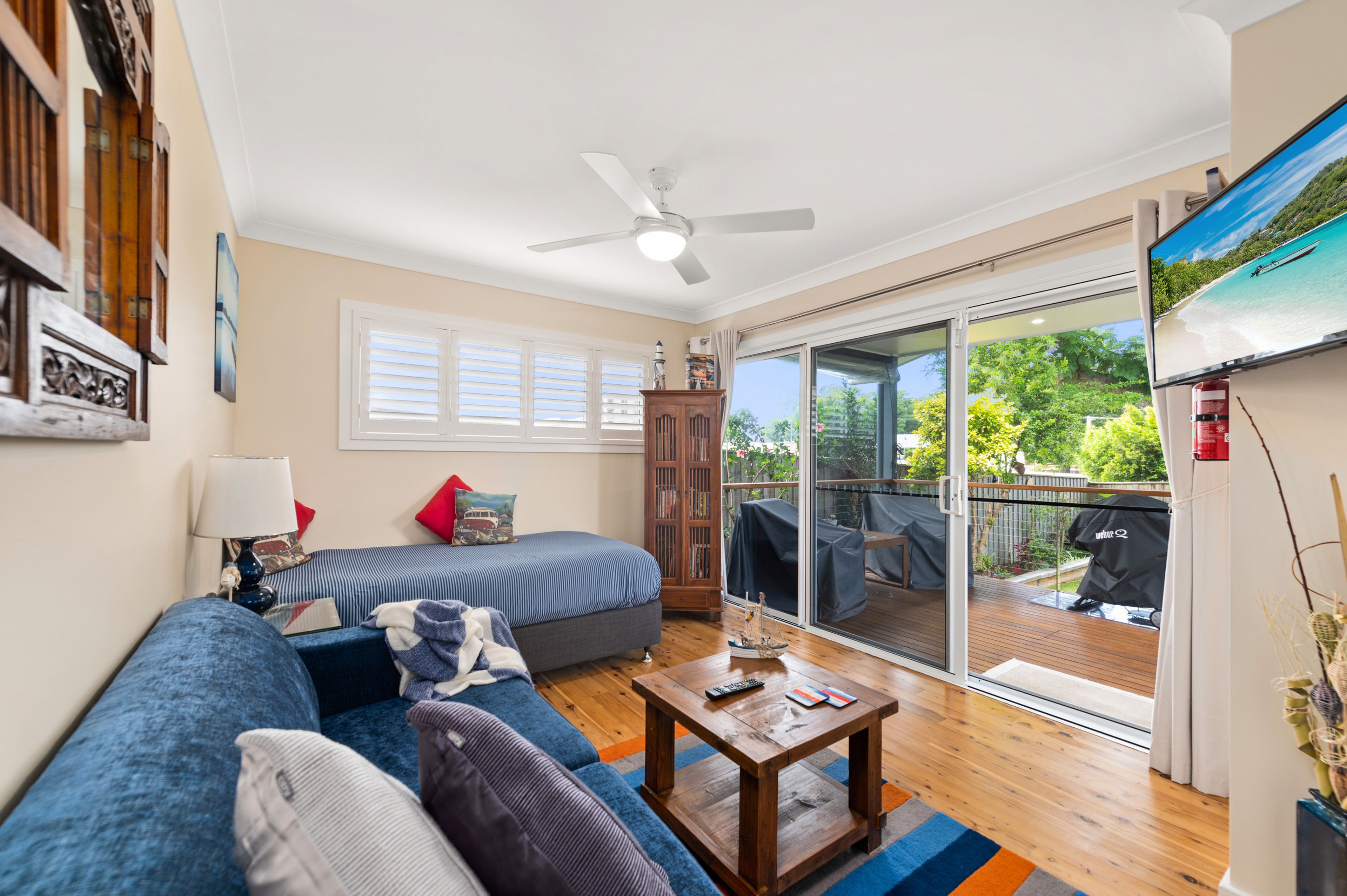 A living room with a sofa, a coffee table, and a television displaying a beach scene.