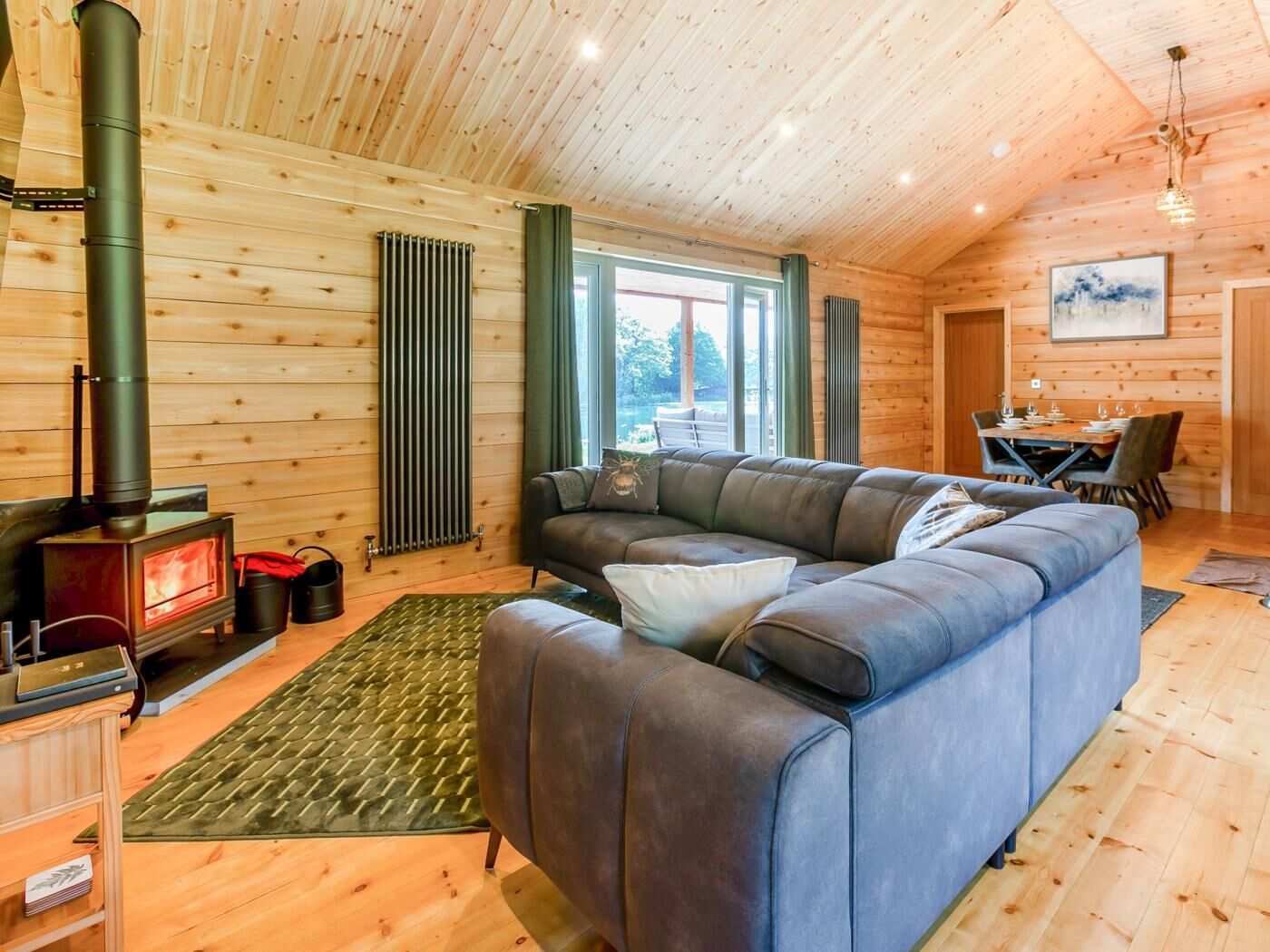 L’intérieur chaleureux d’un chalet avec une cheminée en pierre, un canapé en cuir et un coin repas.