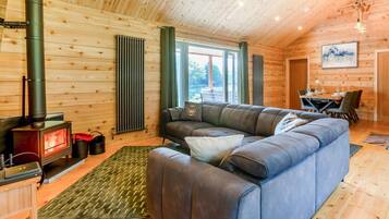 L’intérieur chaleureux d’un chalet avec une cheminée en pierre, un canapé en cuir et un coin repas.