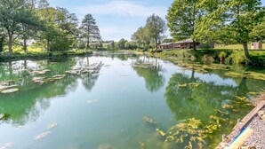 A serene lakeside setting with a row of cabins and a dock extending into the water. - 3 Bed in Cullompton (oc-96118) (Willand)