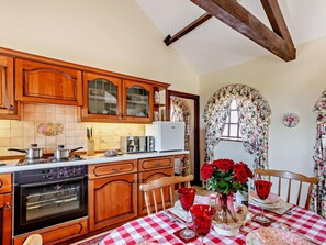 Eine Küche mit Holzausstattung, einer Mikrowelle, einem Backofen und einem Esstisch mit kariertem Tischläufer.