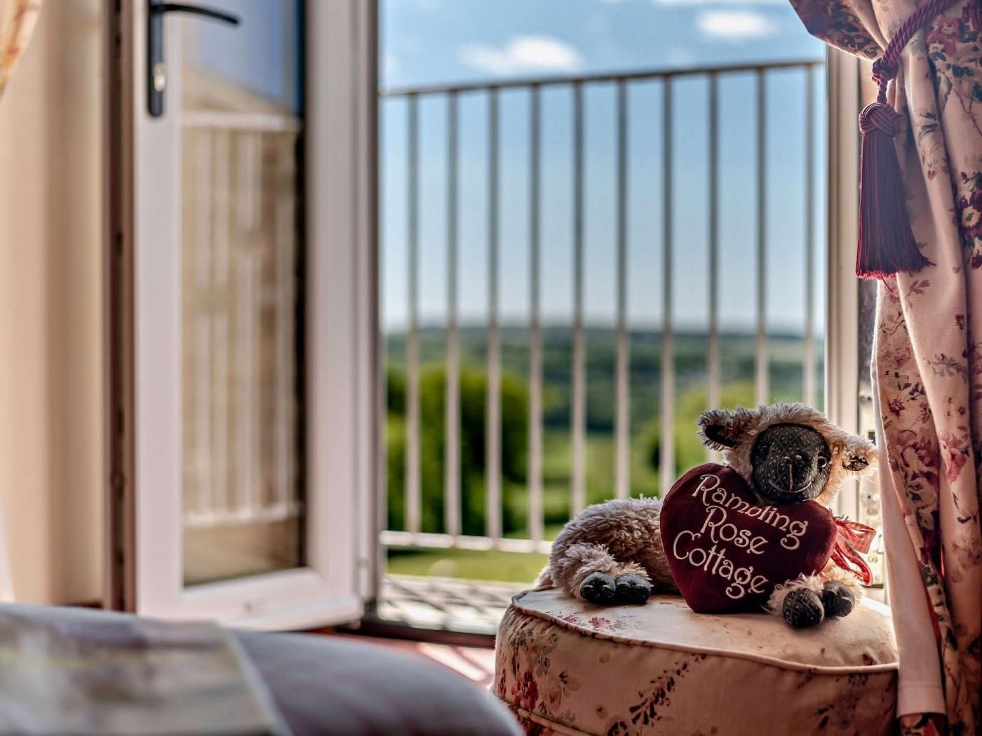 A plush toy with a sign reading 'Daring Rose Cottage' on a window sill.