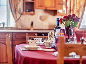 A dining table set with floral tableware and a vase of red roses. - 2 Bed in Wigton (oc-96088) (Ireby)