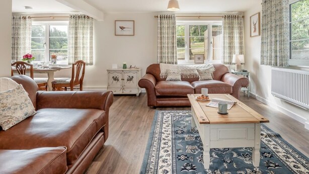 A cozy living room with a brown leather sofa, a wooden coffee table, and a patterned rug. - 3 Bed in Fordingbridge (oc-96126) (Godshill)
