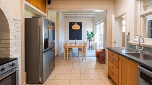 Een moderne keuken met een inbouwoven, een koelkast en een eethoek met een tafel en stoelen.