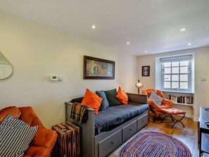 Un accogliente soggiorno con divano, poltrone, un tavolino, una libreria e una finestra.