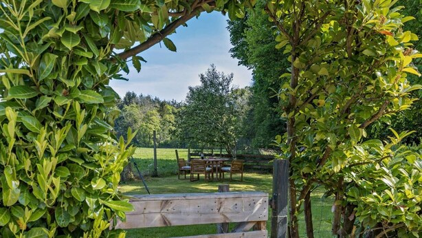 A wooden gate leading to a grassy area with a table and chairs.