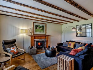A cozy living room with a fireplace, a sofa set, a leather chair, and a floor lamp.