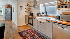 A modern kitchen with wooden cabinets, a built-in oven, a microwave, and a window with blinds.